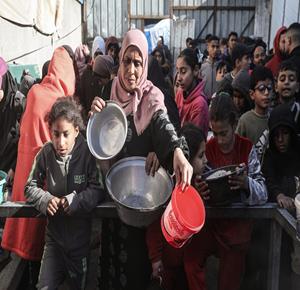 مواطنون يتجمعون للحصول على وجبات طعام مجانية من إحدى التكيات الخيرية في مخيم النصيرات وسط قطاع غزة